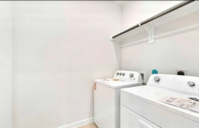 a view of an empty room with window and a kitchen