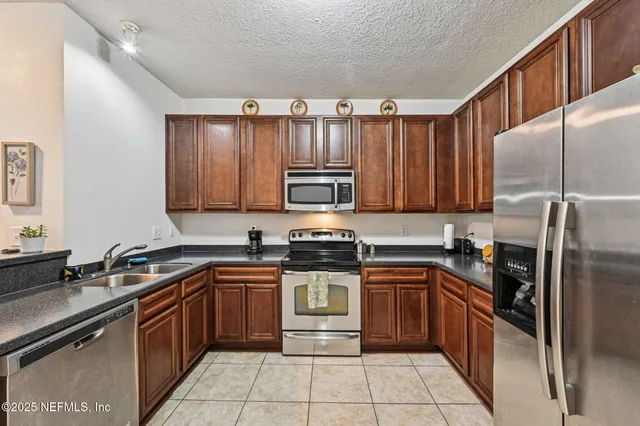 a kitchen with stainless steel appliances granite countertop a stove a sink dishwasher and a refrigerator