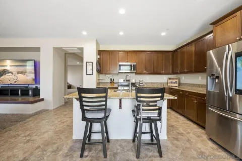 a kitchen with stainless steel appliances kitchen island granite countertop a refrigerator and a stove top oven