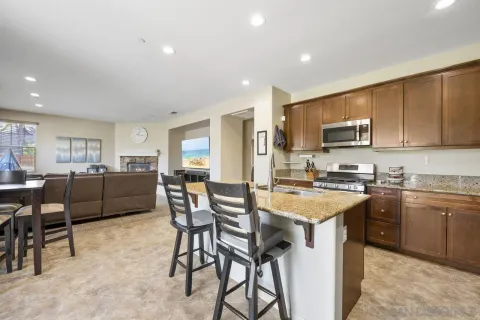 a kitchen with stainless steel appliances granite countertop a table chairs sink refrigerator and cabinets