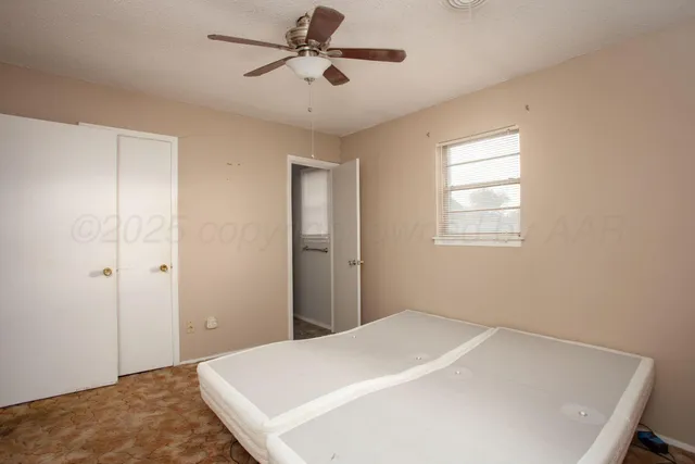 an empty room with windows and fan