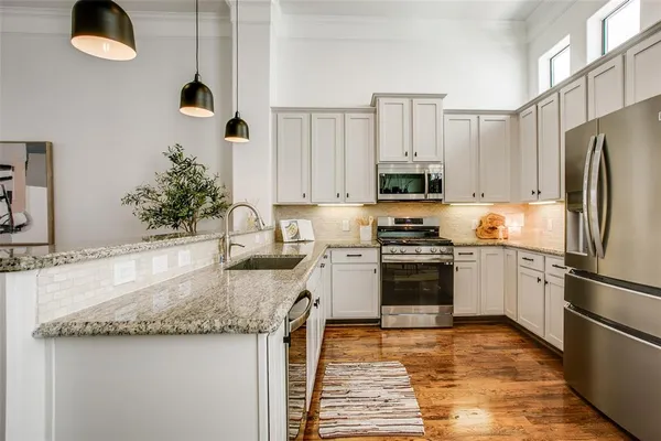 a kitchen with stainless steel appliances a dining table chairs refrigerator and microwave