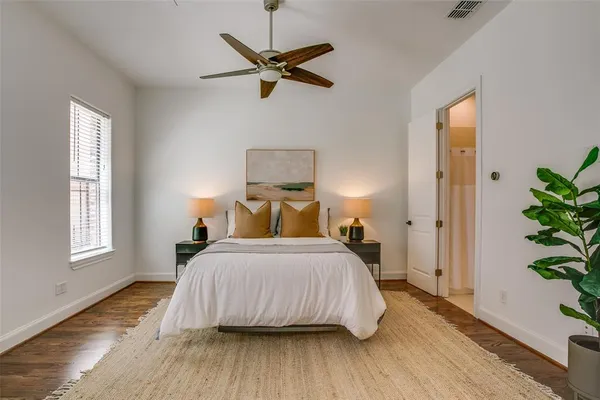 a bedroom with a bed a potted plant on dresser and a wooden floor