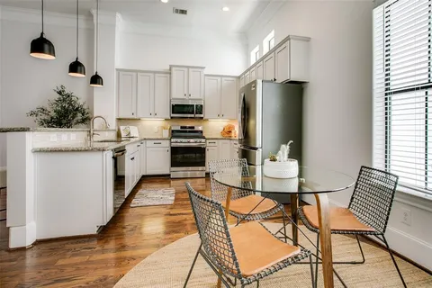 a kitchen with stainless steel appliances granite countertop a stove a refrigerator a kitchen island a table and chairs with wooden floor