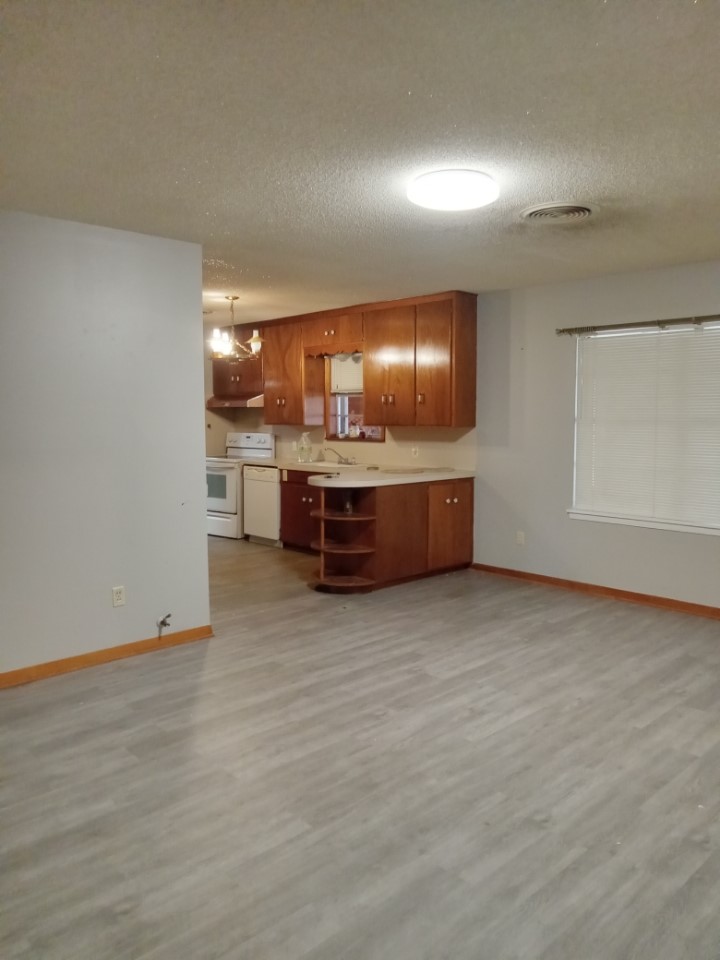 709 West 11th Street Elgin, TX 78621 - Photo 12 of 12 Kitchen featuring wood finish cabinets, a textured ceiling, white appliances, light countertops, and light wood-style floors