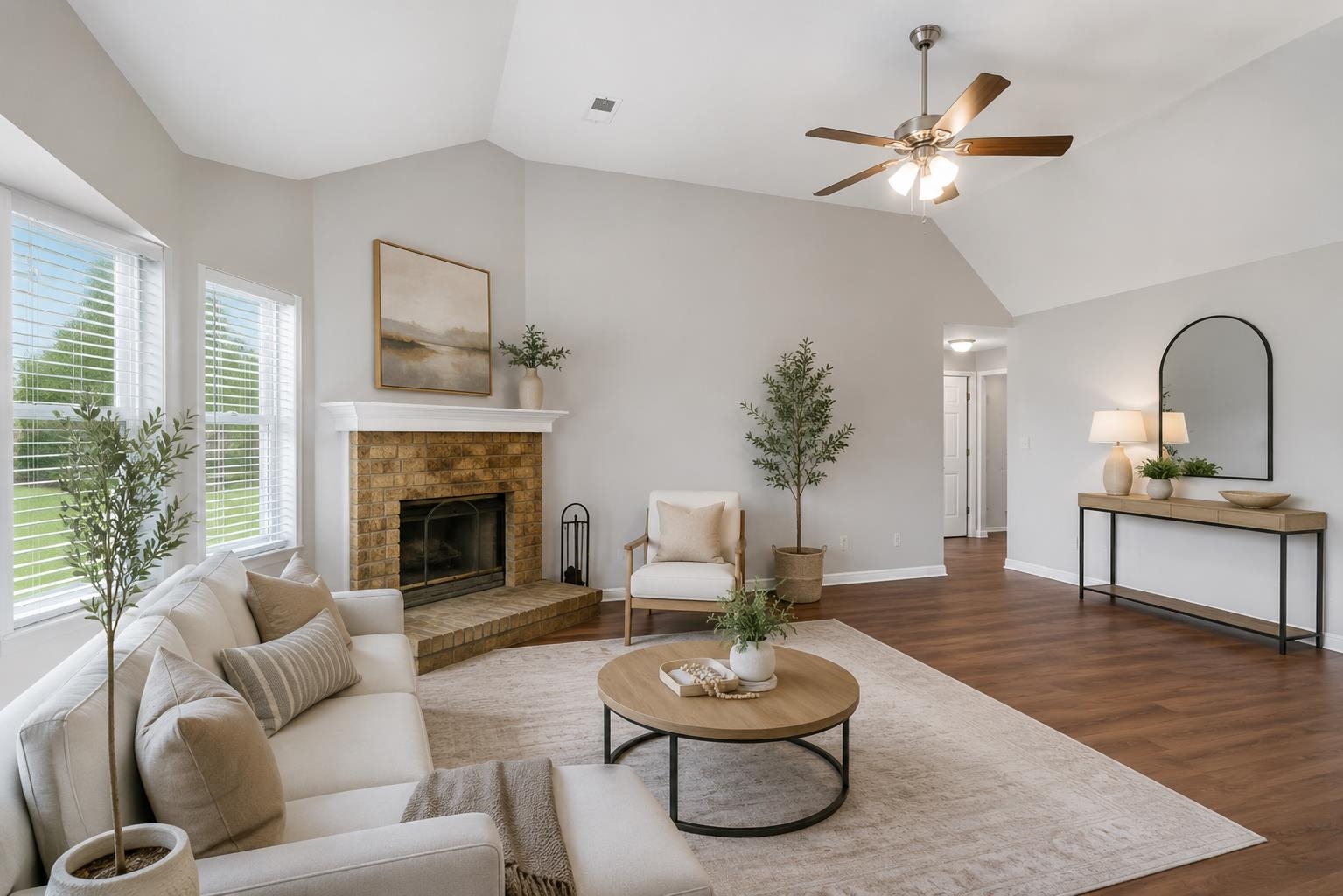 4101 Long Creek Road Memphis, TN 38125 - Photo 6 of 36 Spacious living room featuring a brick fireplace with a white mantel, vaulted ceilings, large windows with blinds, wood-finish flooring, and a ceiling fan
