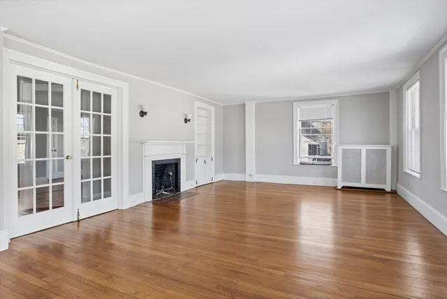 an empty room with wooden floor fireplace and windows