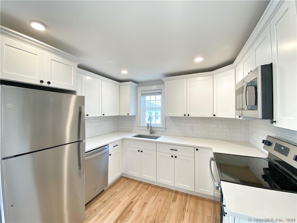32 Pulaski Street, Unit 3 Norwalk, CT 06851 - Photo 1 of 1 a kitchen with a refrigerator a sink and white cabinets