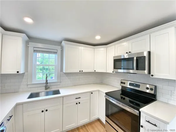 a kitchen with cabinets appliances a sink and a window