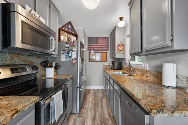 a kitchen with stainless steel appliances granite countertop a sink a stove and a microwave