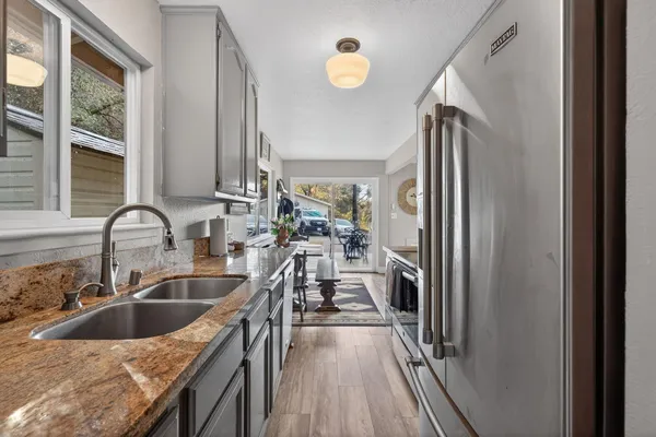 a kitchen with a sink a counter top space a large mirror and stainless steel appliances