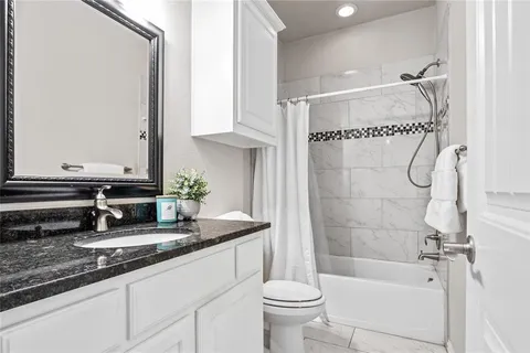 a bathroom with a granite countertop sink a toilet and bathtub