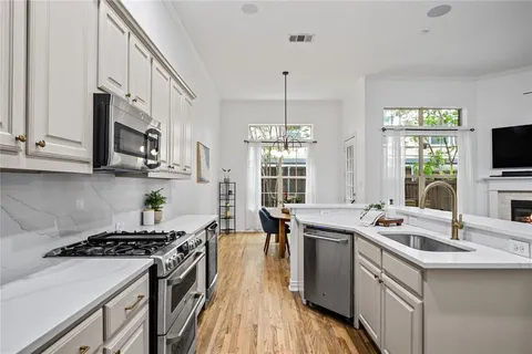 a kitchen with stainless steel appliances a sink stove and wooden floor