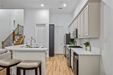 a kitchen with stainless steel appliances kitchen island granite countertop a sink a stove a refrigerator cabinets and chairs