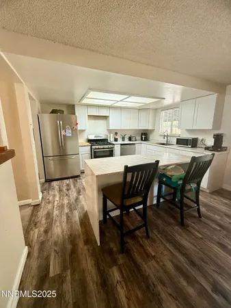 a room with stainless steel appliances a dining table chairs and a refrigerator