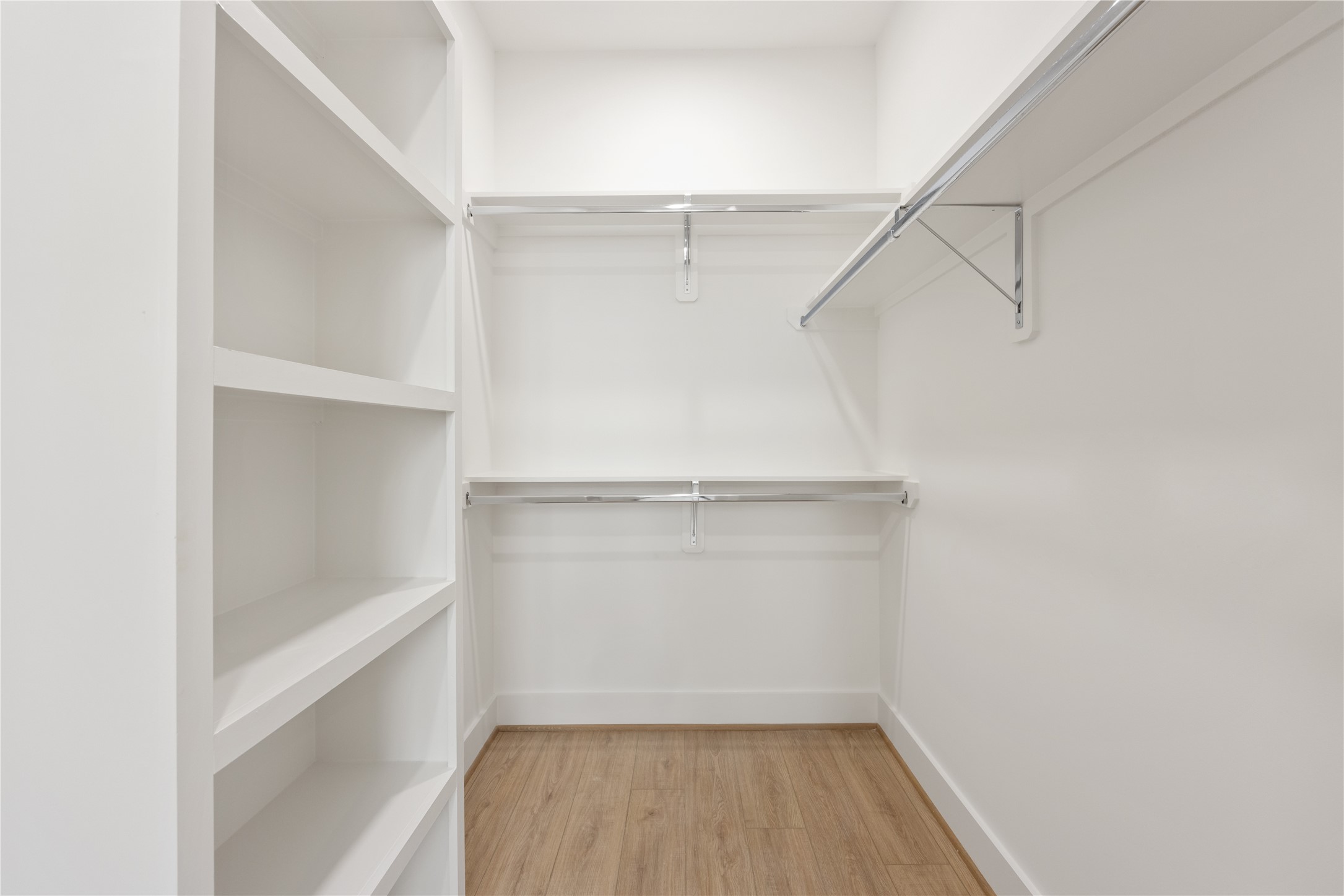 2121 Hoskins Drive, Unit C Houston, TX 77080 - Photo 29 of 34 Walk-in closet with built-in shelving, double hanging rods, and warm wood-look flooring provides organized storage and excellent functionality. The clean white finish keeps the space bright and streamlined, offering room for clothing, shoes, accessories, and seasonal storage.