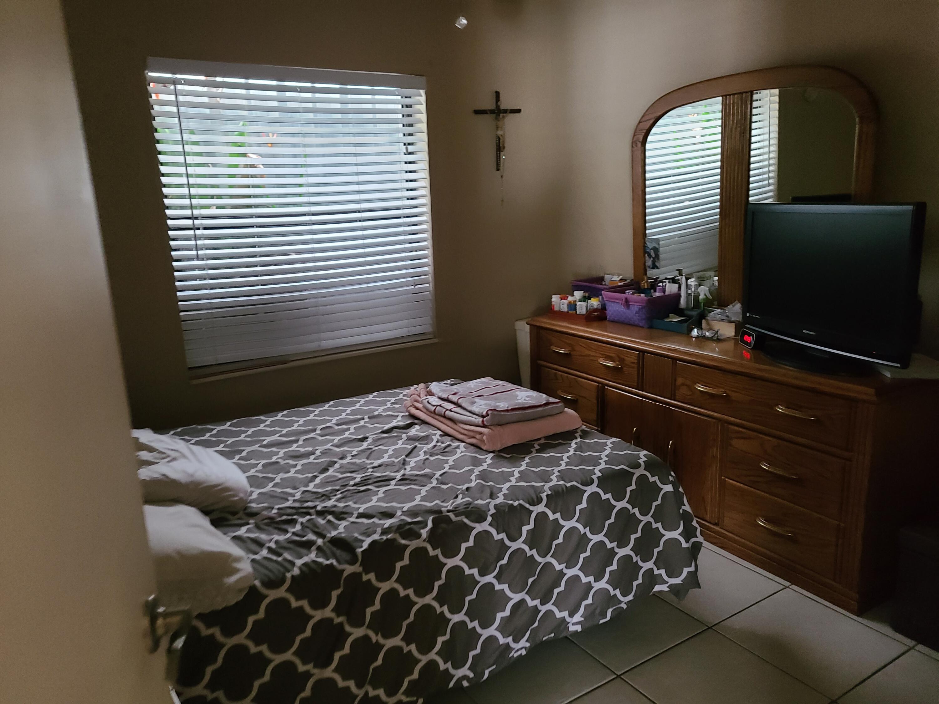 5959 Triphammer Road Lake Worth, FL 33463 - Photo 6 of 10 a bedroom with a bed and a flat tv screen on dresser