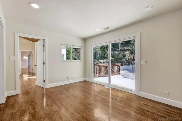 an empty room with wooden floor and ceiling fan