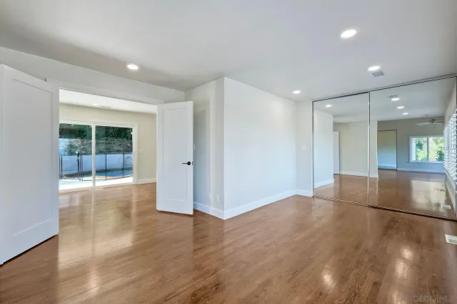 a view of empty room with wooden floor and fan