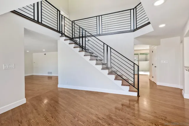 a view of an empty room with wooden floor and a fireplace