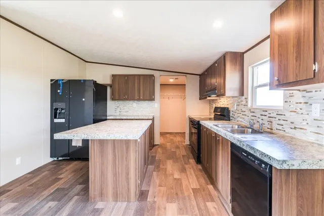 a kitchen with a stove a sink a refrigerator and wooden floor