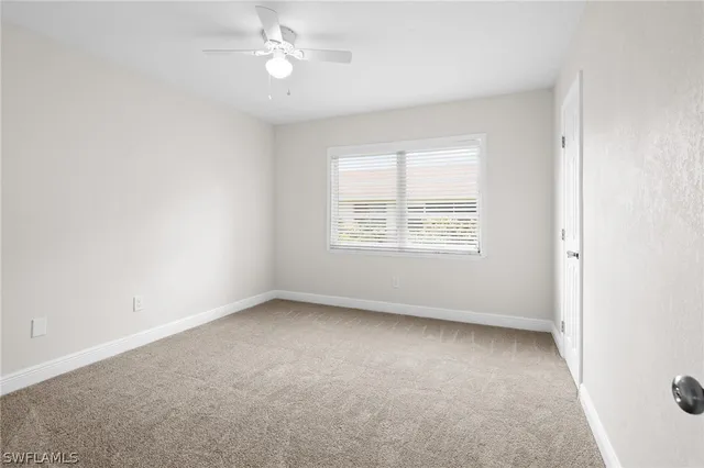 an empty room with a window and ceiling fan