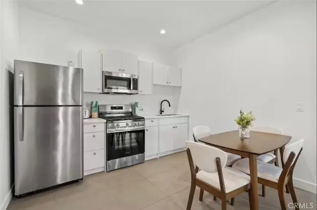 a kitchen with stainless steel appliances a refrigerator a stove a sink a microwave a stove and white cabinets