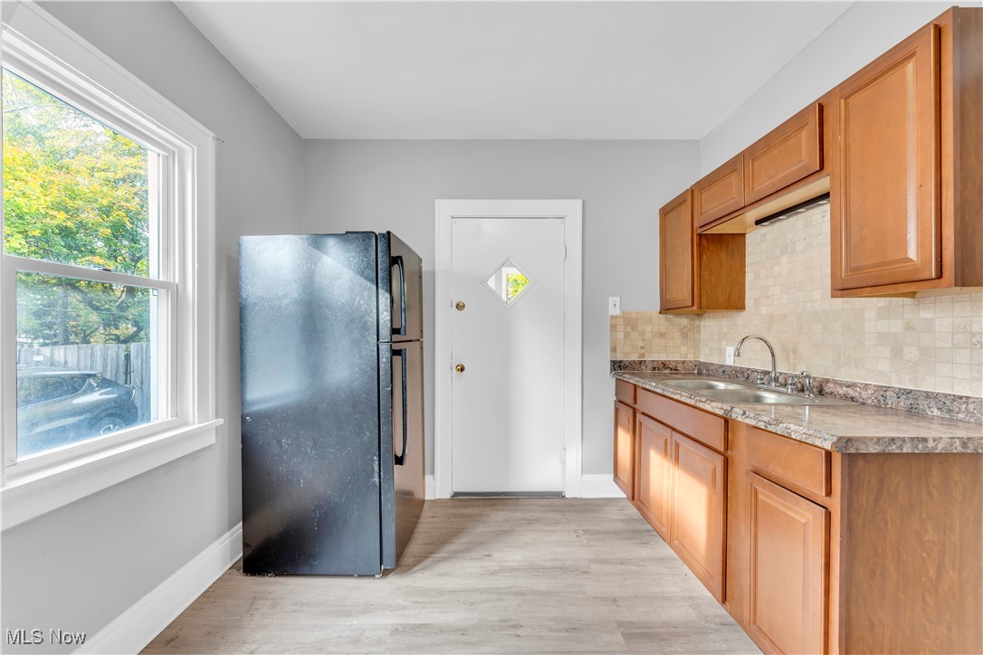 3245 Oak Road Cleveland, OH 44118 - Photo 11 of 24 Kitchen featuring light hardwood / wood-style flooring, decorative backsplash, sink, and black fridge