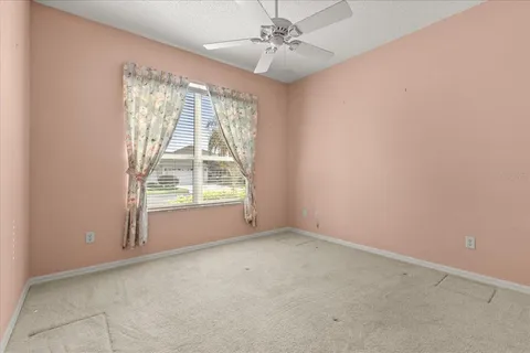 en empty room with windows and chandelier fan