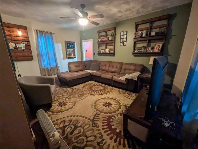 a living room with furniture a flat screen tv and a refrigerator