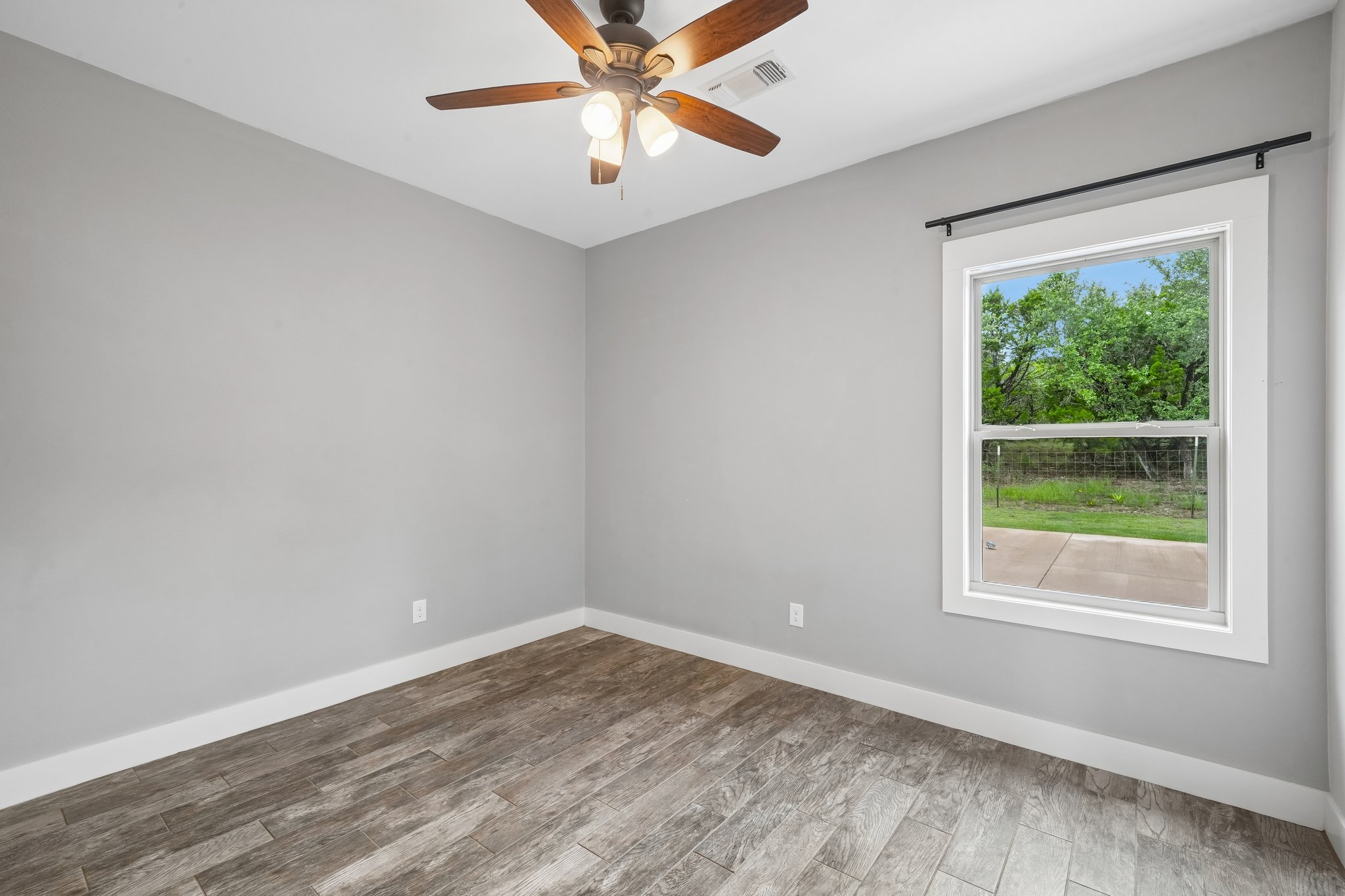 190 Magnolia Meadow Spring Branch, TX 78070 - Photo 14 of 29 A quiet bedroom offers wood-look flooring and a window overlooking lush green scenery.