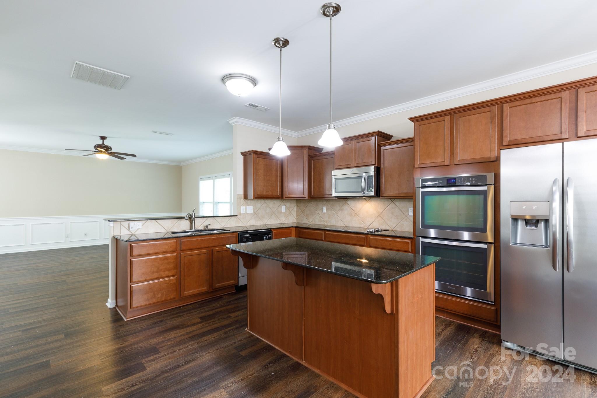 2219 Bluebell Way Fort Mill, SC 29708 - Photo 14 of 48 a kitchen with stainless steel appliances granite countertop a stove a refrigerator and a sink with wooden cabinets