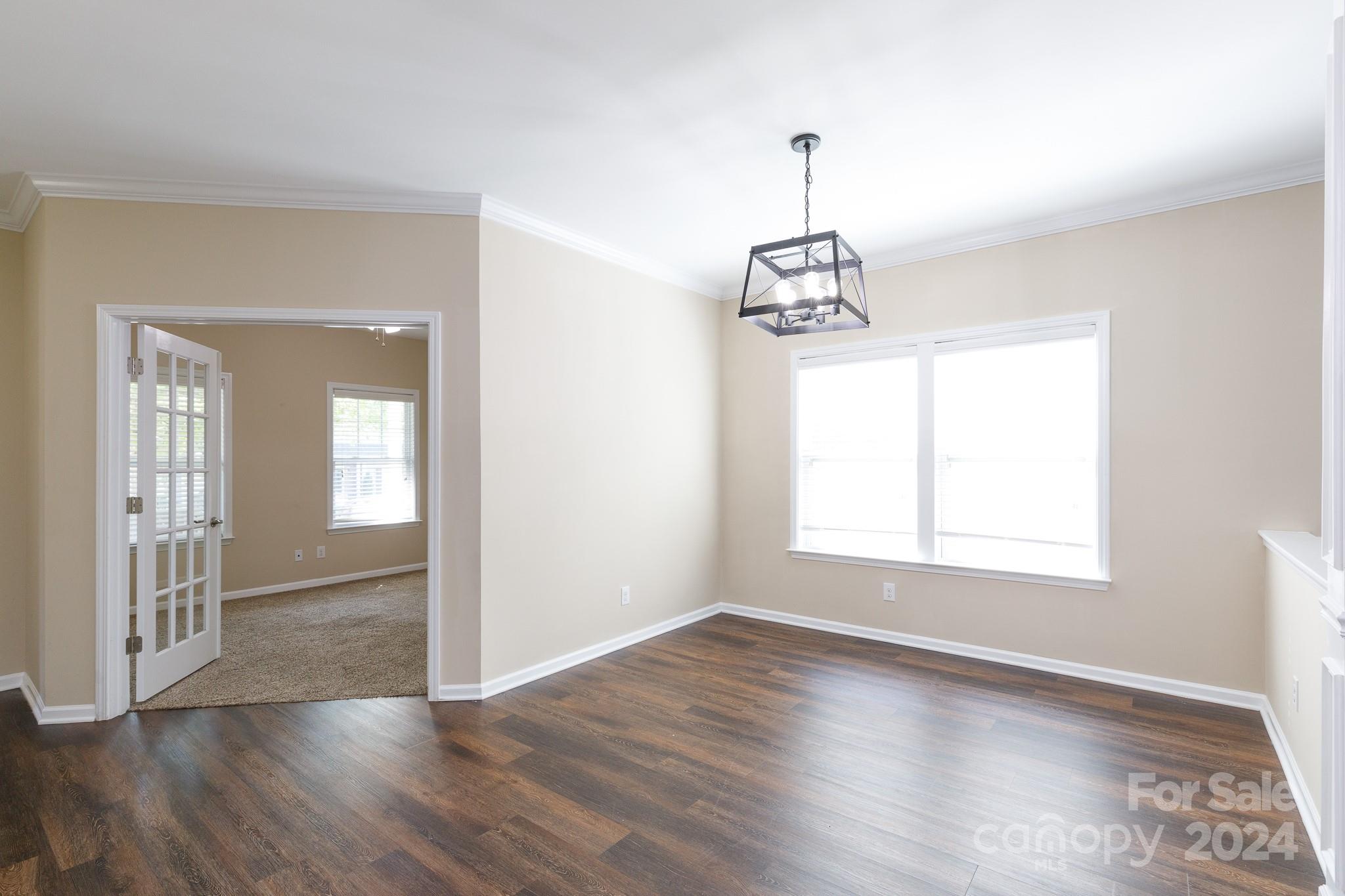 2219 Bluebell Way Fort Mill, SC 29708 - Photo 7 of 48 an empty room with wooden floor windows and a chandelier
