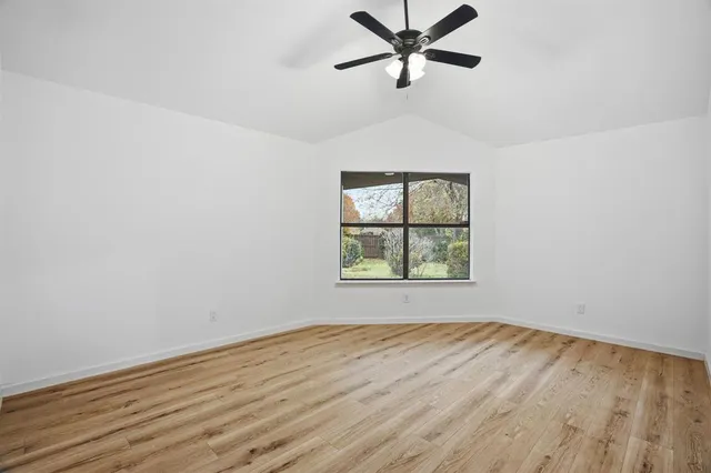 an empty room with wooden floor fan and windows