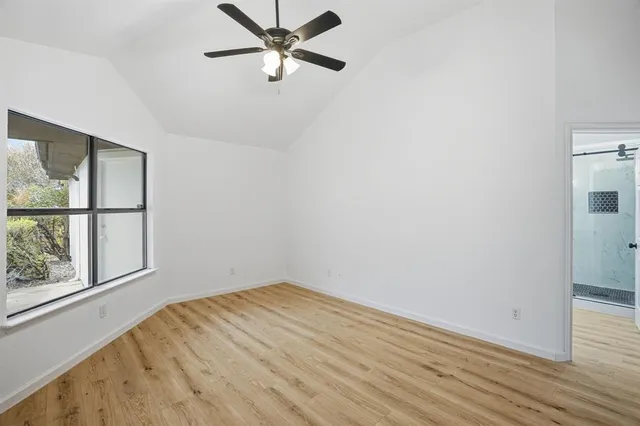 a view of empty room with wooden floor and fan