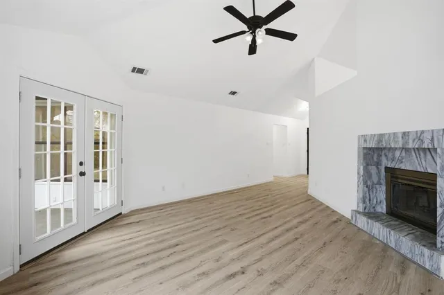 an empty room with wooden floor fireplace and windows
