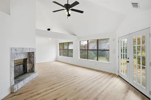 an empty room with wooden floor fireplace and windows