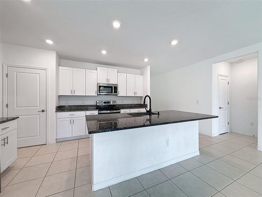 4395 Trotters Way Lakeland, FL 33801 - Photo 9 of 67 a large kitchen with stainless steel appliances granite countertop a sink and white cabinets