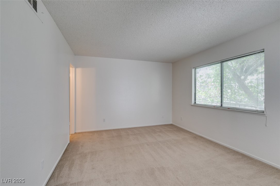 2681 Ruthe Duarte Avenue Las Vegas, NV 89121 - Photo 29 of 43 Empty room featuring baseboards, visible vents, light colored carpet, and a textured ceiling