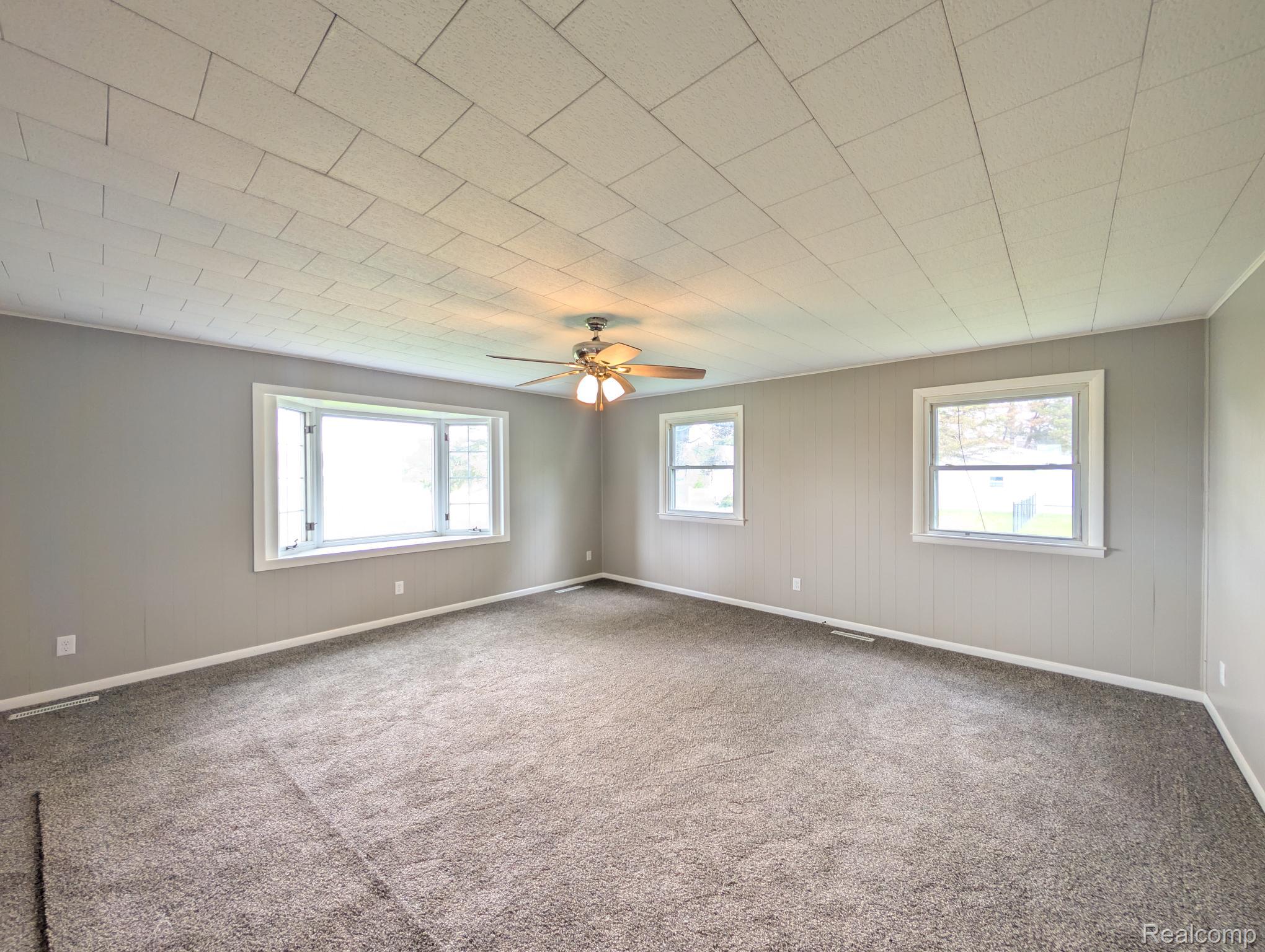 7032 Neff Road Mount Morris, MI 48458 - Photo 14 of 20 Empty room featuring plenty of natural light, carpet floors, a ceiling fan, and wood walls