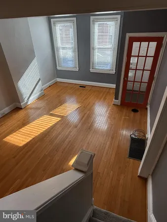 a view of an empty room with wooden floor and window