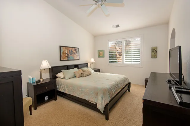 a bedroom with a bed and a flat tv screen on dresser