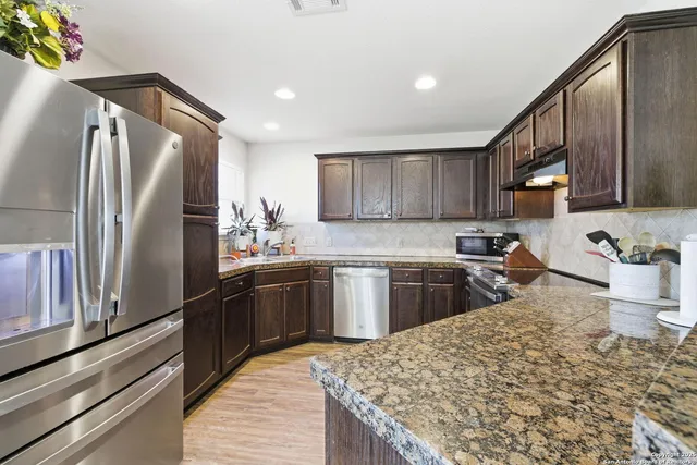 a kitchen with stainless steel appliances granite countertop a refrigerator sink and cabinets