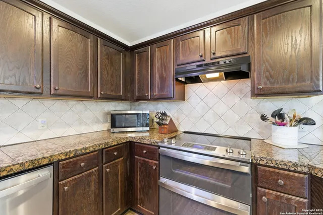 a kitchen with granite countertop cabinets stainless steel appliances and a counter space
