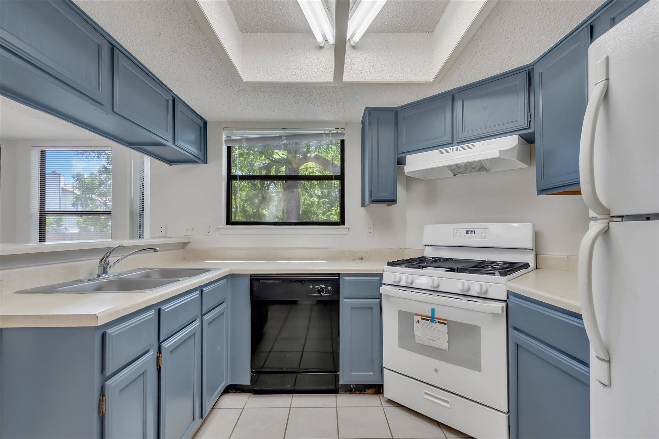 7802 Topawa Cove, Unit B Austin, TX 78729 - Photo 10 of 32 A kitchen with sleek, blue-toned cabinetry and essential appliances awaits your culinary touch.