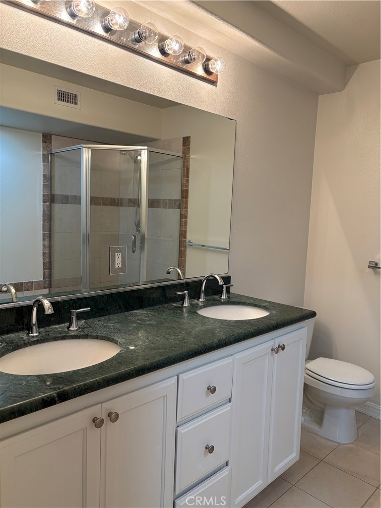 10207 Mountair Avenue, Unit 105 Tujunga, CA 91042 - Photo 24 of 32 a bathroom with a granite countertop sink a toilet and a mirror