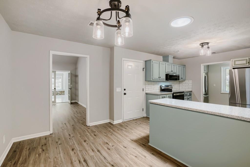 2021 Irwin Bridge Road Northwest Conyers, GA 30012 - Photo 11 of 43 a kitchen with stainless steel appliances granite countertop a refrigerator a stove oven a sink dishwasher and white cabinets with wooden floor