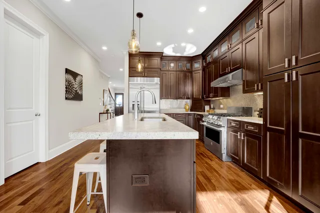 a kitchen with stainless steel appliances granite countertop a sink a stove and a refrigerator