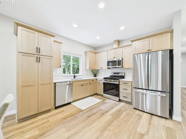 a kitchen with granite countertop stainless steel appliances a refrigerator cabinets and wooden floor