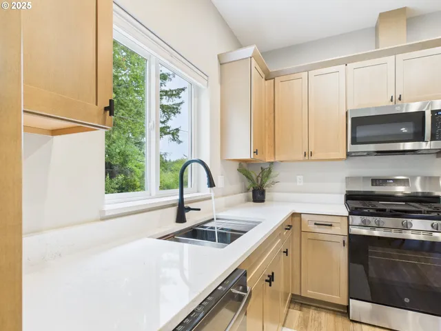 a kitchen with stainless steel appliances a sink a stove a microwave and cabinets